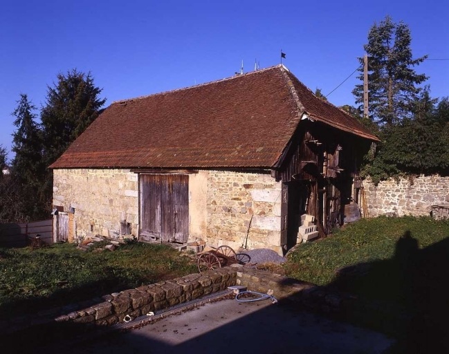 Vue d'un grand bâtiment agricole, à deux niveaux, regroupant à la fois une grange, une étable à brebis, une remise, une buanderie, un poulailler et un pigeonnier.