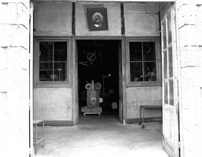 L'entrée des ateliers de 1883 (porte-fenêtre ouverte). Le portrait de Jules Dutreix, fondateur de la fonderie, est suspendu au-dessus de la porte des anciens bureaux des ateliers, transformés en atelier de mécanique.