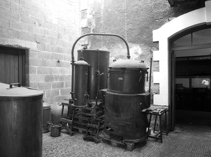 Cour couverte reliant le chai et le laboratoire de la distillerie : le sol est pavé d'anciennes gazettes pour la cuisson de la porcelaine. La Distillerie du Centre expose ici deux alambics construits par la 'Chaudronnerie Industrielle Larouquie Louis' à Brive (17).