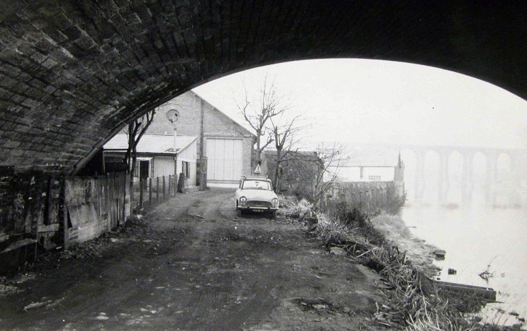 Photographie de l'usine, prise depuis le quai de la Vienne, sous une arche du pont de la Révolution, non datée.