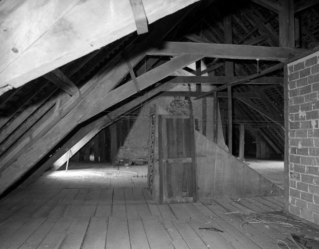 Etage de comble. Vue partielle montrant la cage d'escalier en bois et la charpente constituée de fermes avec faux entraits.