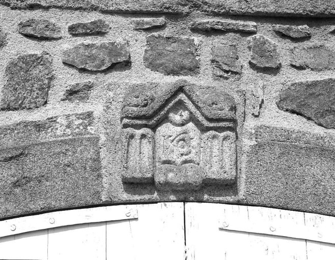 Elévation antérieure du logis. Détail du décor sculpté en bas-relief ornant le linteau de la porte centrale du rez-de-chaussée.