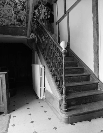 Intérieur, rez-de-chaussée. Vue de la première volée de l'escalier avec rampe en fer forgé.