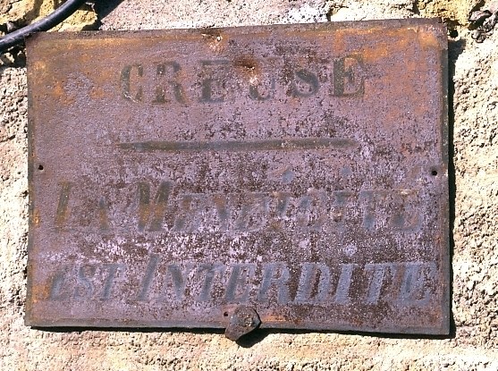Plaque fixée sur une maison de la rue Grancher (n° 30, AL 457) et mentionnant que 'la mendicité est interdite'.