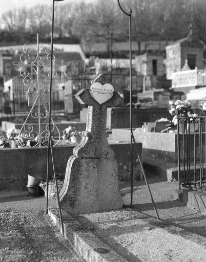 Tombe avec croix en granite ornée d'un coeur en métal émaillé.