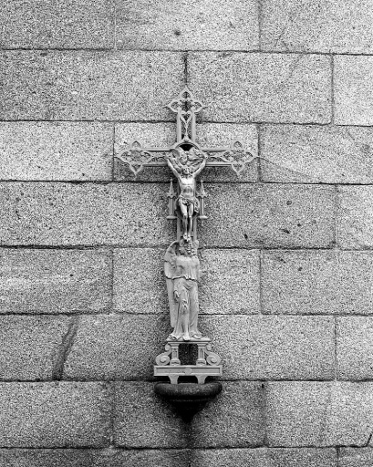 Croix en métal accolée à l'élévation ouest de la chapelle blanche.