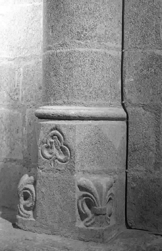 Colonne nord de la nef située entre la 2e et 3e travée. Vue de détail du décor sculpté ornant la base et représentant un trèfle et deux fleurs de lys.