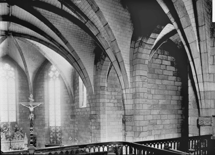 Vue partielle de l'intérieur de l'église, prise depuis la tribune, au début du 20e siècle et montrant l'autel du choeur et un christ en croix fixé au garde corps de la tribune.