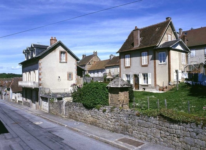 Route de Crocq ; 6 et 8 rue de Beaumont. Maisons (AM 105, 461, 462). Vue d'ensemble, depuis la route de Crocq montrant des édicules de jardin réalisés en rocaille ; au premier plan, sont visibles les latrines d'une maison, et en arrière-plan, la couverture d'un puits.