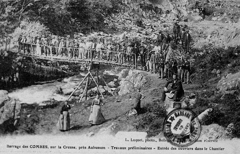 Le site sur la Creuse, avant la réalisation du barrage ; les ouvriers, employés à la construction, posant sur le pont provisoire. A noter, le cachet apposé en bas à droite de la carte postale mentionnant 'barrage des Combes près Aubusson / cantine du barrage'.