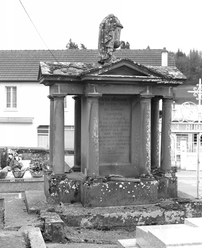 Tombe (tombe n° 1). Tombe réalisée en pierre de Volvic ; cette tombe en forme de petit temple, est composée d'un massif quadrangulaire formant stèle et dont les quatre faces, précédées chacune de deux colonnes, sont couronnées d'un fronton triangulaire. Vue d'ensemble.