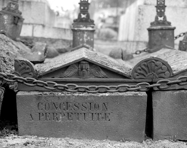 Ensemble de trois tombes (tombes n° 2). Vue de détail du décor sculpté de la tombe centrale représentant un sablier ailé.