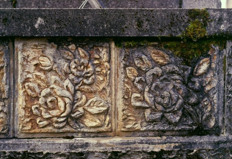 Tombe n° 16. Tombe ornée de plaques réalisées en ciment armé, à la manière des rocailleurs et représentant un décor floral. Détail d'une plaque.