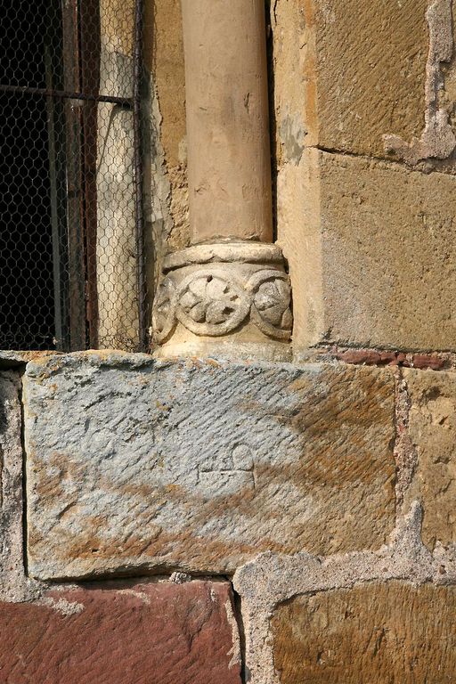 Baie axiale, vue extérieure. Détail de la base de la colonnette de droite ornée d'un décor de feuillages sculpté dans une frise de trois médaillons.