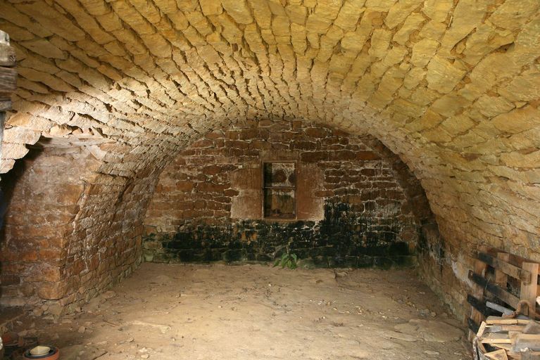 Vue générale de la cave voûtée en berceau édifiée en moellon de calcaire équarri.