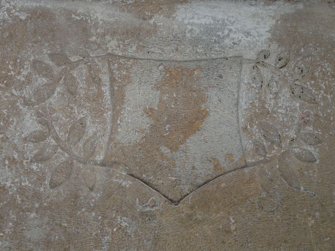 Détail du blason orné de rinceaux de lauriers, dont les armoiries ont été bûchées