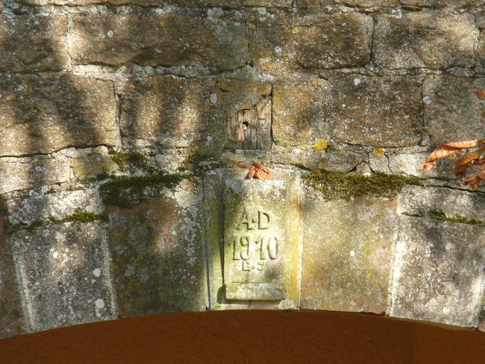 Détail de la date 1910 ornée des initiales A.D et B.J inscrite sur le linteau de la porte charretière centrale de la grange-étable.