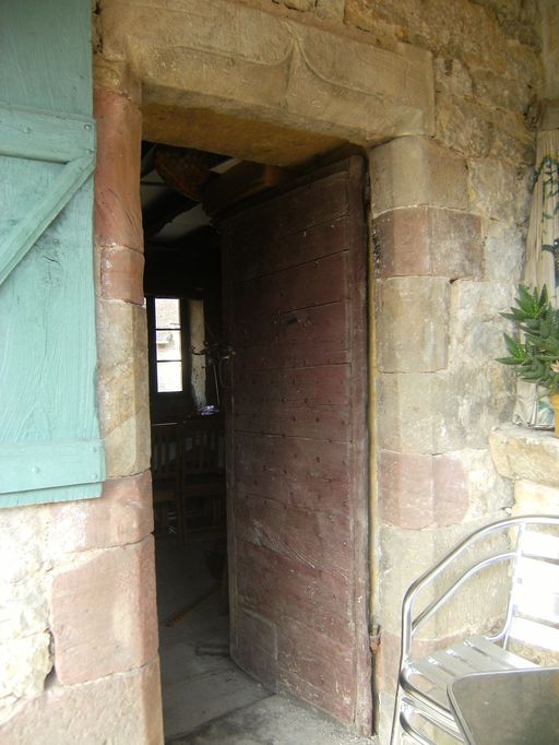 Porte d'entrée chanfreinée surmontée d'un linteau monolithe orné d'un arc en accolade.