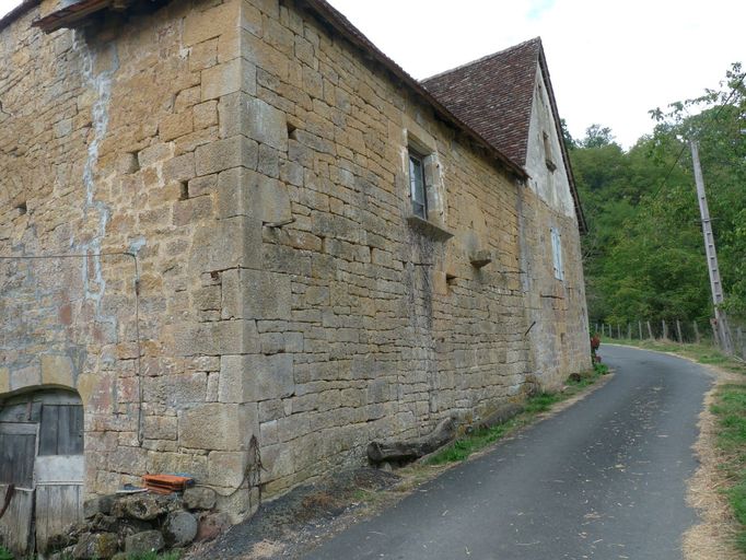 Mur gouttereau est de l'extension du logis percé d'un baie chanfreinée à appui saillant. Mur de croupe sud, porte charretière en arc déprimé.