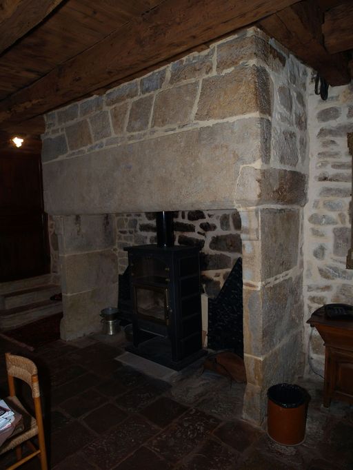 Cheminée adossée en maçonnerie surmontée d'un linteau monolithe en calcaire. Sur les piédroits, en partie bûchés, des départs de volute sont conservés.