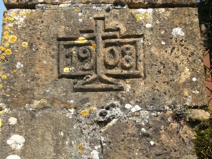 Détail de la date 1908 inscrite dans un cartouche et ornée d'une croix située sur le pilier droit du portail d'entrée.