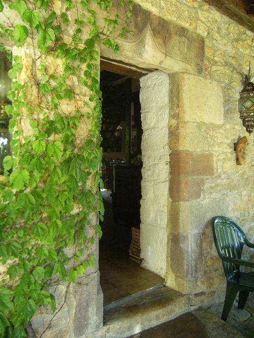 Porte piètonne chanfreinée à congés triangulaires surmontée d'un arc en accolade (en remploi).