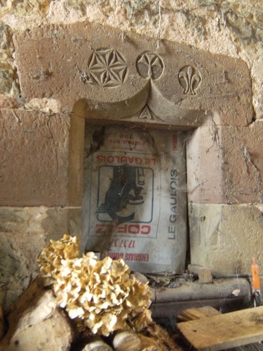 Fenestron chanfreiné en arc en accolade orné d'une rosace, d'une fleur et d'une fleur de lys..