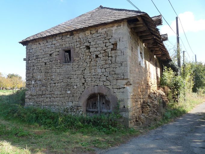 Leygonie. Maison (limite 14e-15e siècle). ; Vue générale du mur de croupe ajouré d'un baie chanfreinée à appui saillant mouluré et d'une porte de cave chanfreinée en arc en plein-cintre.