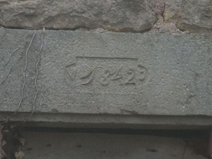 Mur-pignon nord : détail de la date 1842 inscrite dans un cartouche sur le linteau de la porte en arc segrmentaire située sur le mur-pignon nord.