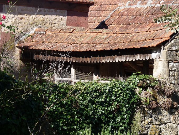 Vue générale du séhoir à maïs : les rives du toit présentent un décor de lambrequin en bois découpé.