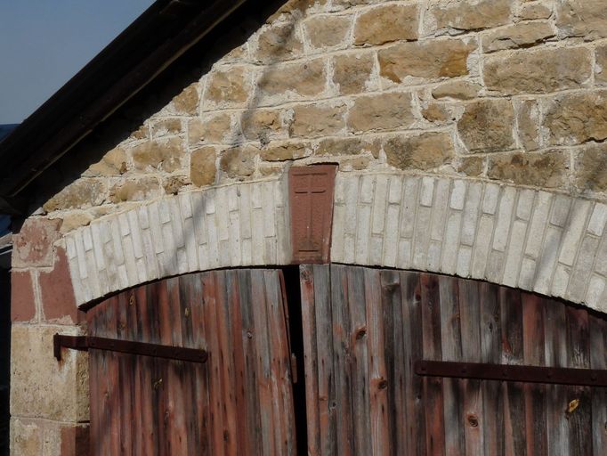 Grange-étable de type limousin : détail de la clé en grès rouge ornée d'une croix.