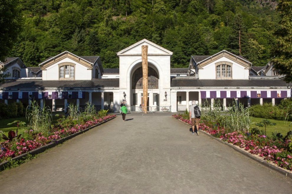 Vue de l'entrée des thermes encadrée par la colonnade avec au centre le brandon préparé pour la fête de la Saint-Jean.