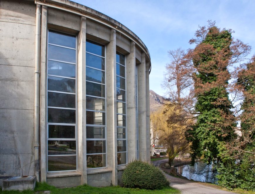 Vue extérieure de la rotonde de la piscine répondant à la courbe du lac du parc.