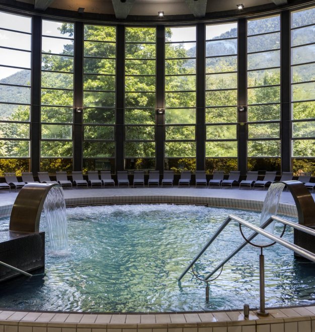 Vue de la piscine de relaxation et des baies ouvrant sur le paysage.