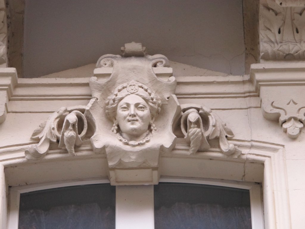 Façade : détail du décor de la baie à gauche du rez-de-chaussée, tête féminine.