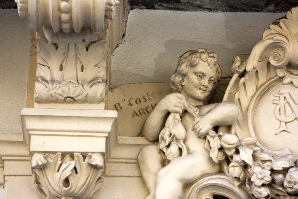Groupe sculpté surmontant la porte : détail de l'enfant de gauche avec signature de l'architecte Castex.