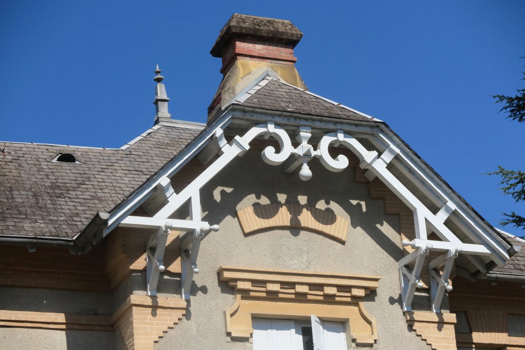 Vue de l'avant-toit de la façade est de la maison avec décors des aisseliers et des décharges en bois avec volutes affrontées.