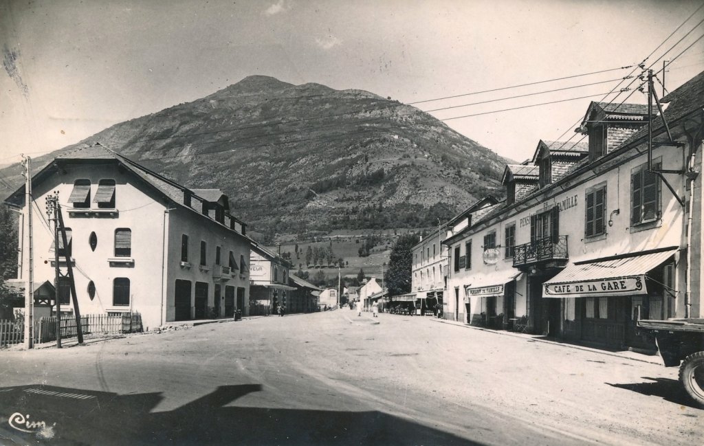Route de la gare: bâtiment des voyageurs à l'arrière-plan à gauche ; café de la gare et hôtel Terminus à droite