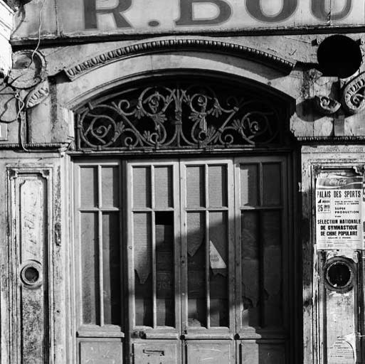 Façade principale, détail de la grille de tympan de l'ouverture de boutique à droite de la porte.