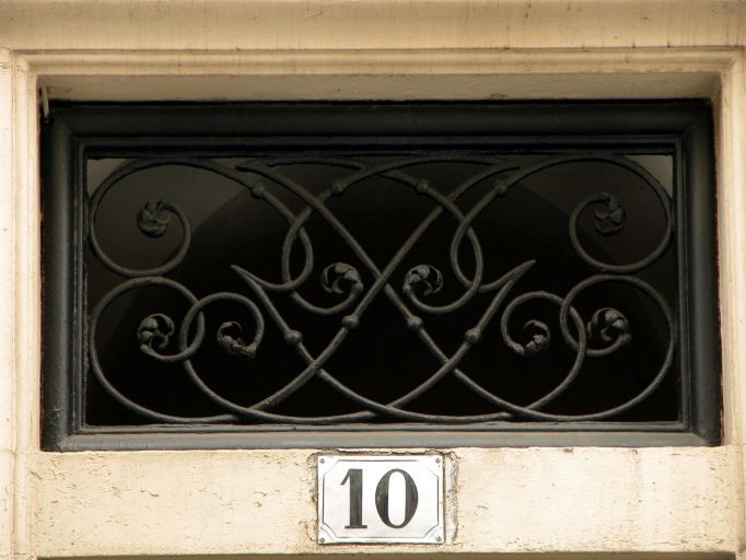 Façade sur rue, détail de la grille du jour en dessus de porte.