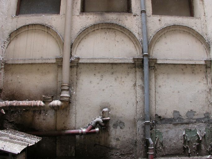 Cour, élévation nord, arcades murées du 1er étage.