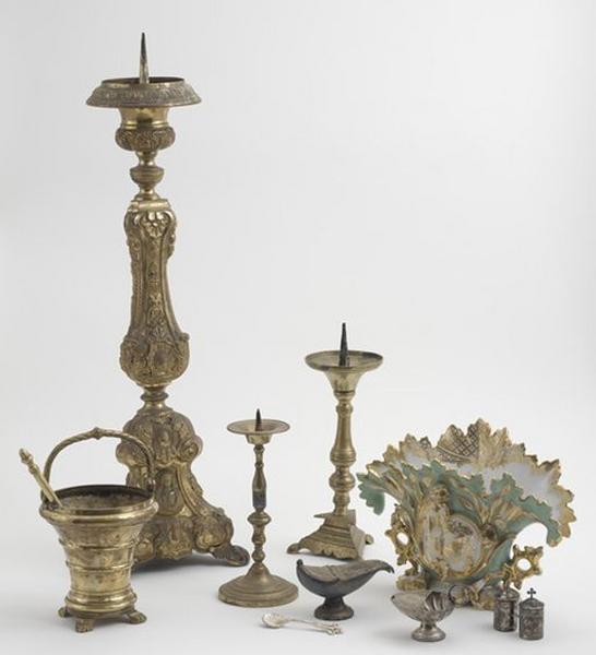 Vue générale de différents objets : un chandelier d'autel de l'ensemble de 2, un seau à eau bénite, deux croix d'autel, un vase d'autel, une coquille de baptême, une navette à encens, un ensemble de deux ampoules aux saintes huiles.