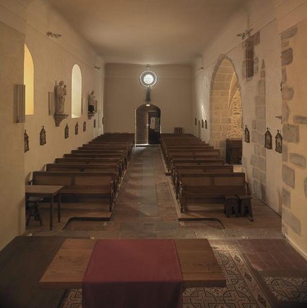 Vue intérieure de la nef en direction de l'entrée avec l'emplacement des fonts baptismaux dans le mur nord.