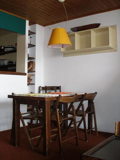 Appartement traversant sur 2 demi-niveaux. Le coin-repas, la niche de rangement, le luminaire et l'étagère en plastique moulé. Mobilier d'origine dessiné par Monique Labro