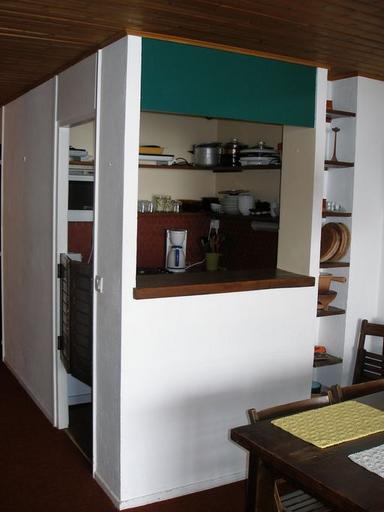 Appartement traversant sur 2 demi-niveaux. Le passe-plat formant séparation entre le coin-repas et la cuisine. Mobilier d'origine dessiné par Monique Labro