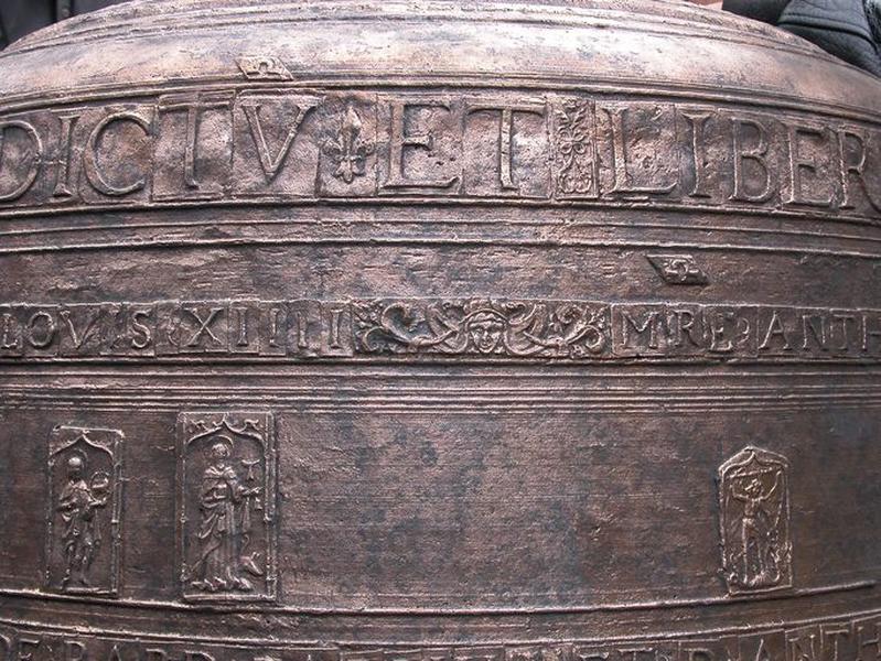 Cloche (n°1), détail du cerveau de la cloche avec plaquettes avec caractères, fleur de lys, masque, inscription du roi Louis XIIII, médaillons rectangulaires représentant saint Jean-Baptiste, saint Antoine abbé et saint Michel terrassant le dragon.