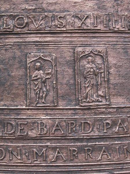 Cloche (n°1), détail de plaquettes avec caractères et deux médaillons rectangulaires représentant saint Jean-Baptiste et saint Antoine abbé.