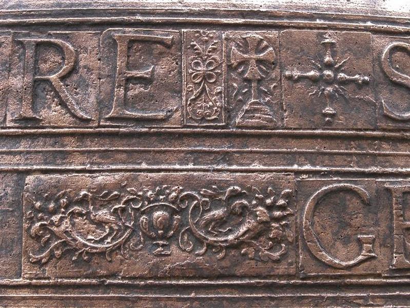 Cloche (n°1), détail de plaquettes avec caractères et de médaillons comprenant des cornes d'abondance avec oiseaux, une croix grecque pattée et une autre croix grecque avec bras en forme de balustre tourné.