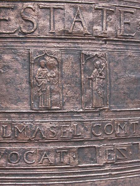 Cloche (n°1), détail de plaquettes avec caractères, de deux médaillons rectangulaires avec, à gauche, saint Pierre avec une clef, et à droite, saint Paul avec une épée et une palme.
