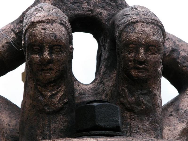 Cloche (n°1), détail de deux anses et de leur visage en bas-relief.